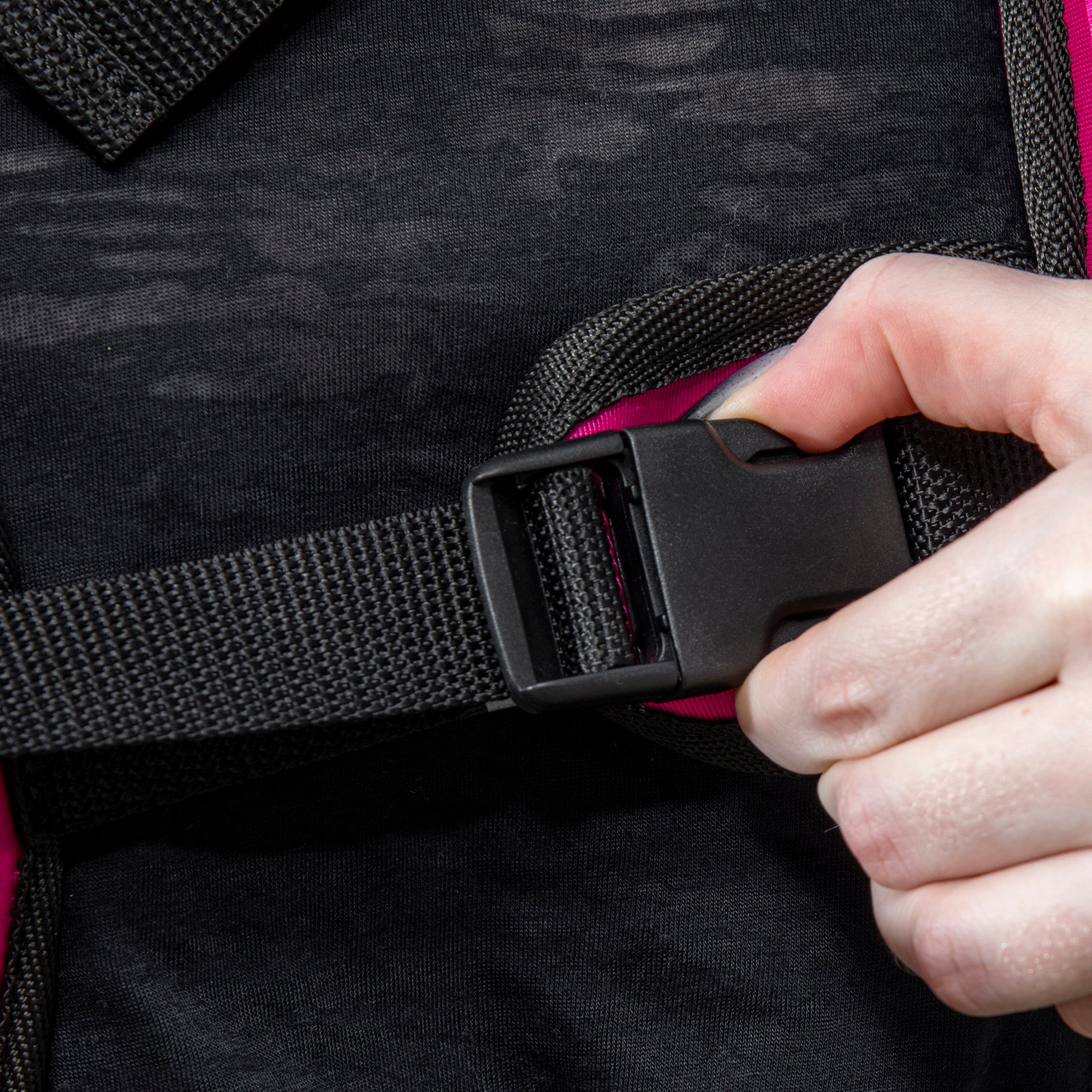 Close-up of black buckle and strap on pink weighted vest for adjusting fit
