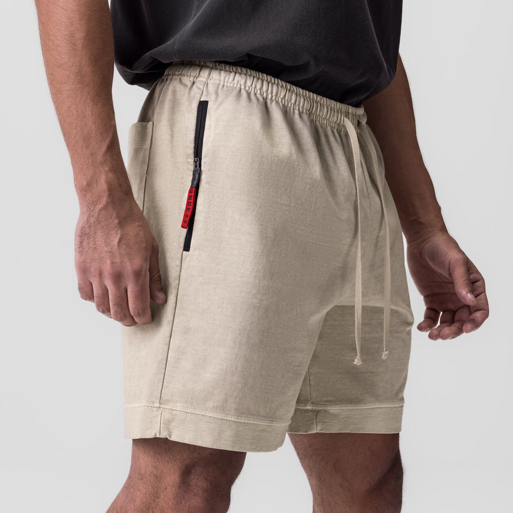Beige training shorts with elastic waistband, drawstring, and vertical side zip pocket