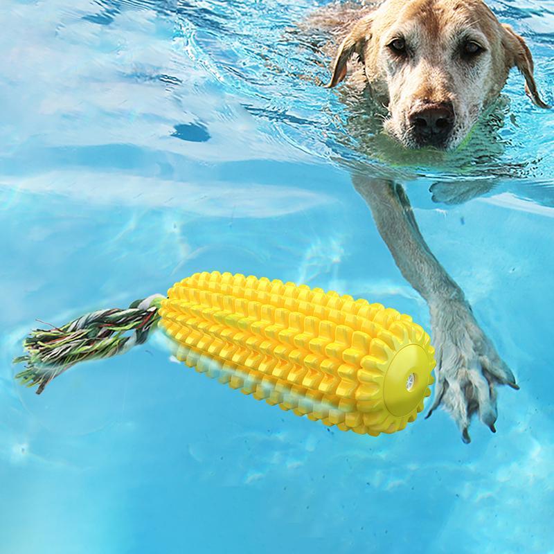 Yellow ridged corn chew toy with green cotton rope tail in a swimming dog’s mouth