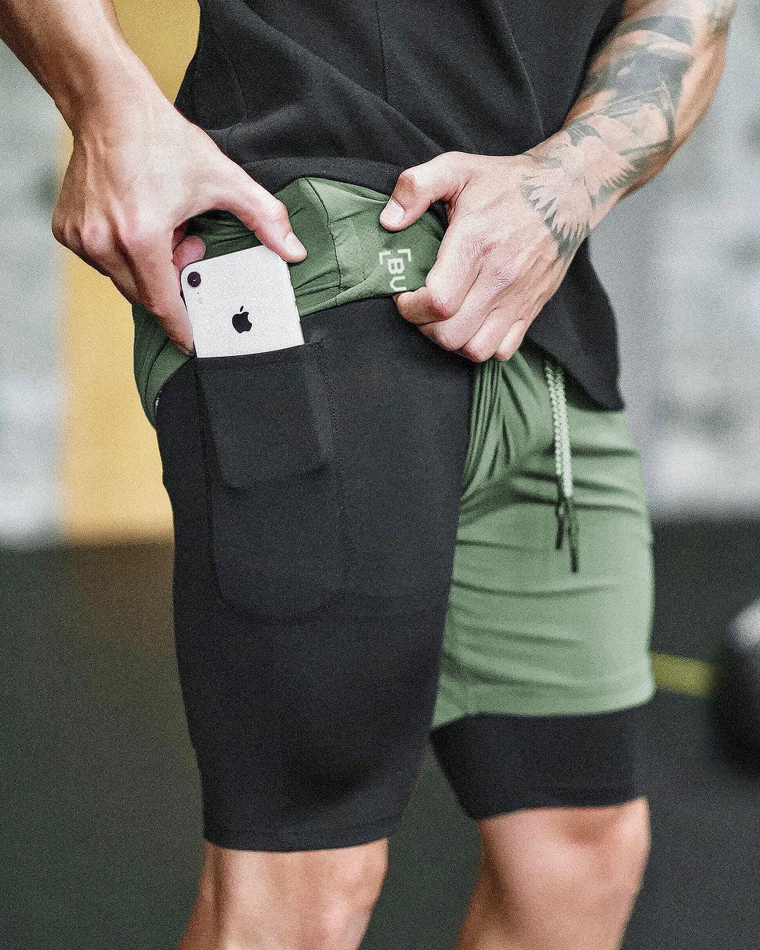 Men's athletic shorts with large side pocket, green waistband, drawstring ties