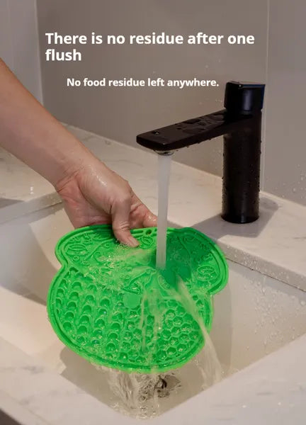 Green pet licking mat being rinsed in a sink with water running over the surface