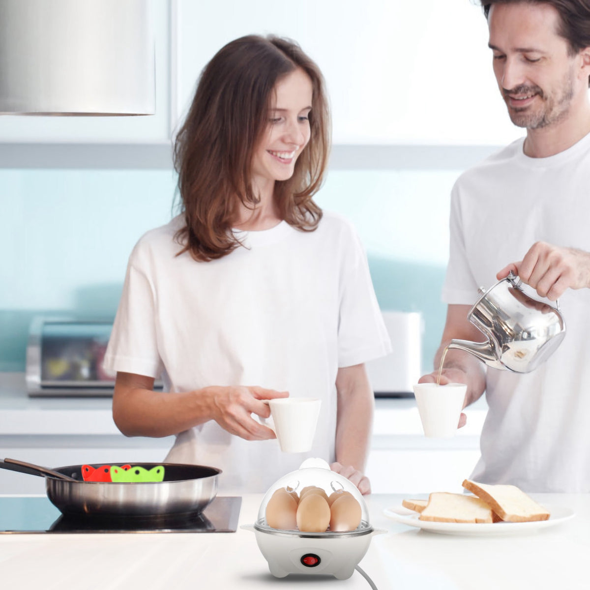 White electric egg cooker with clear lid, brown eggs inside, and red power button on table