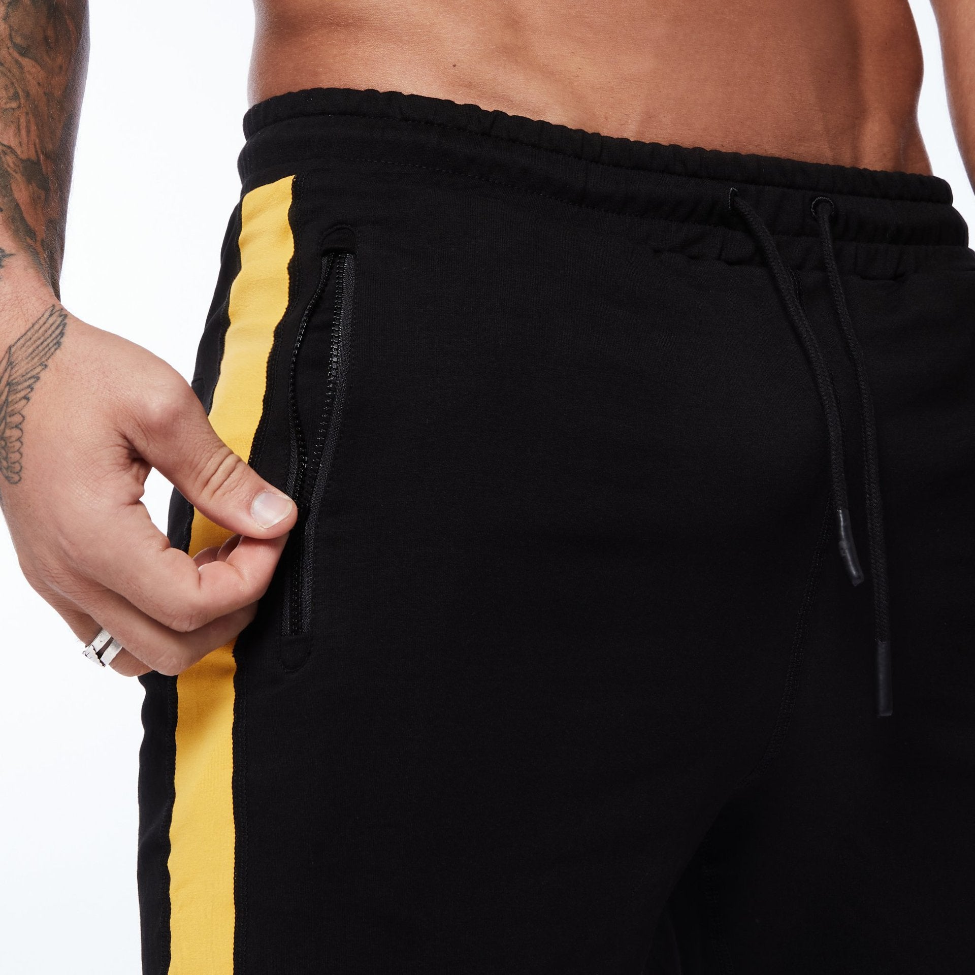 Black running shorts with yellow side stripe, zip pocket, and drawstring