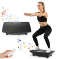 Black vibration plate with remote control, shown during use with a person