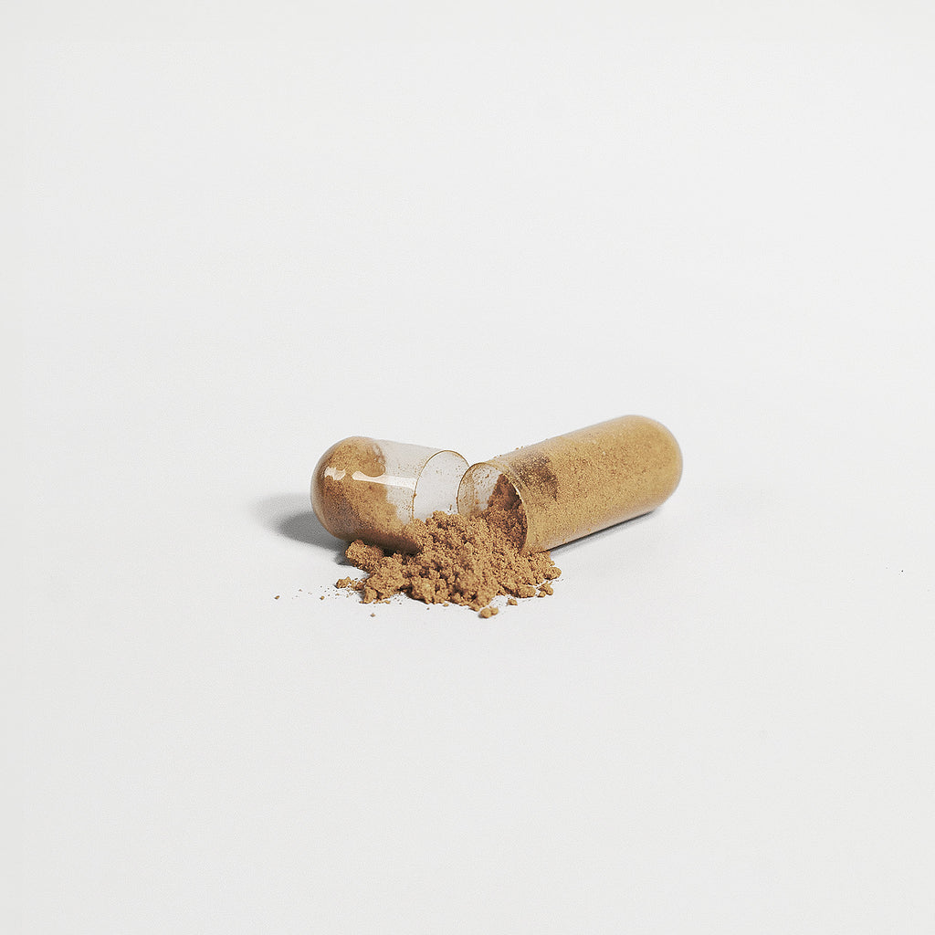 Gold-colored softgels with powder spill on a clean surface