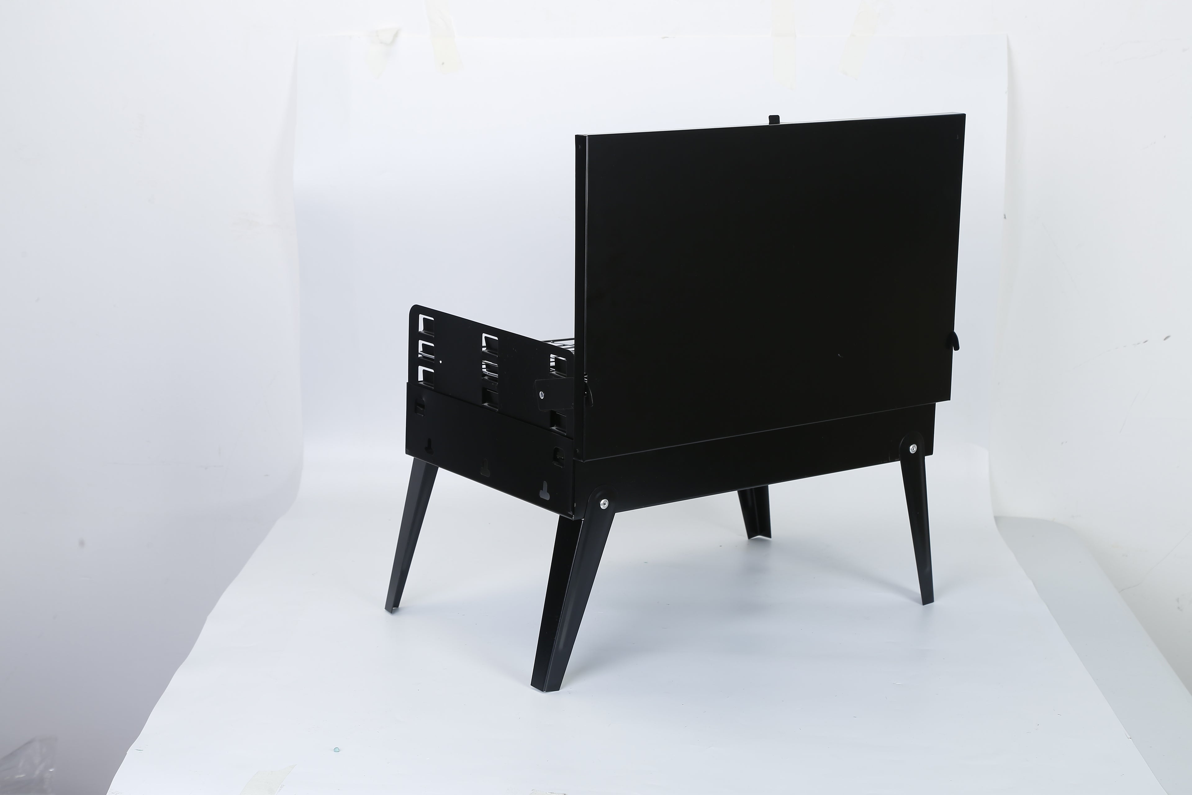 Black portable BBQ grill with lid closed, folding legs and front latch handle