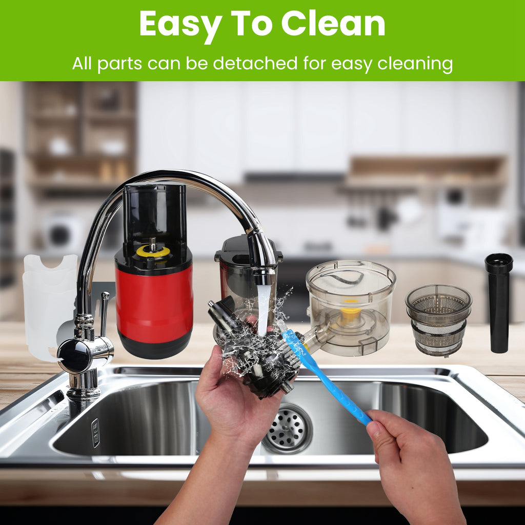 Red cold press juicer with clear parts rinsed in sink, showing detachable components.