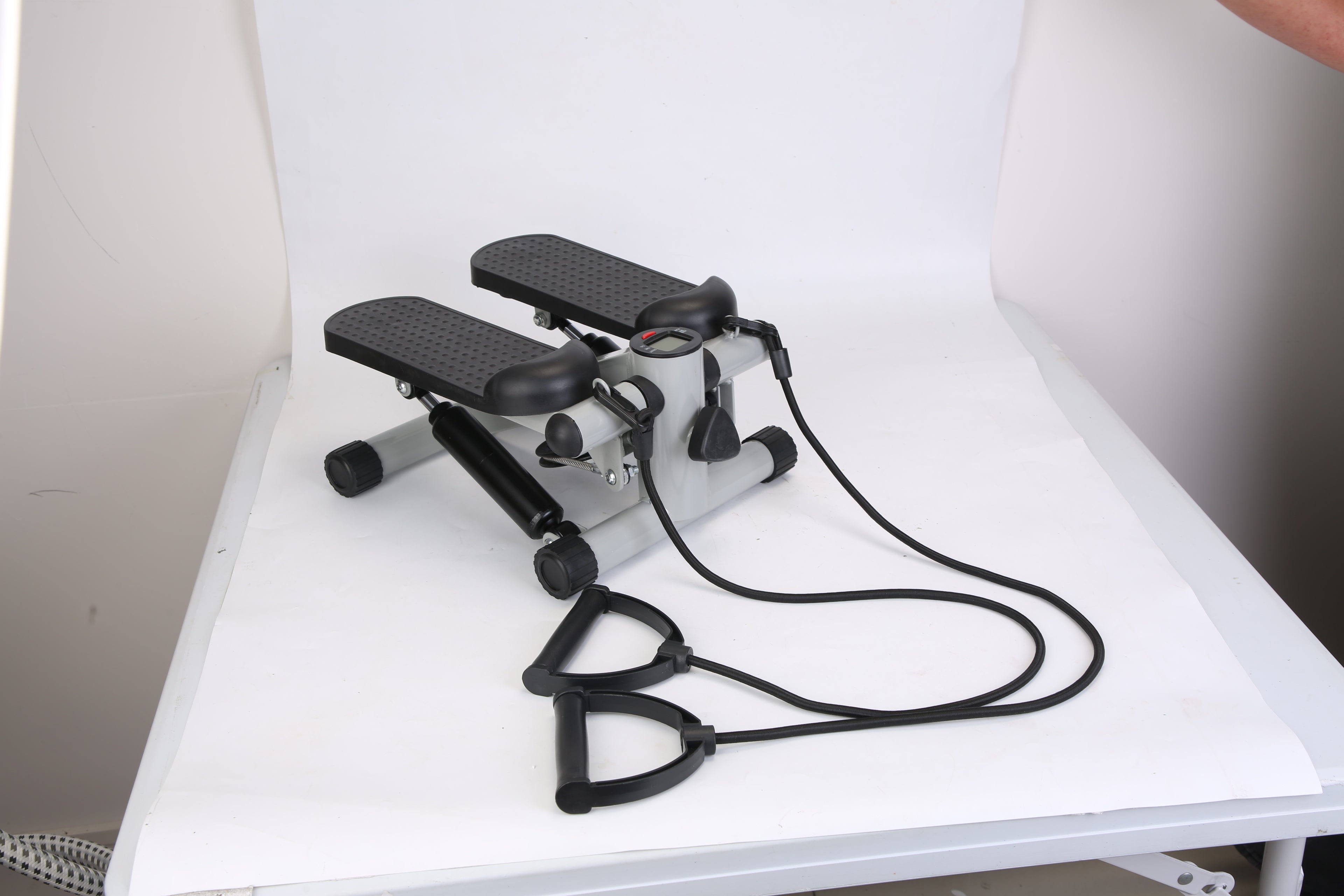 Mini fitness stepper with black step pads, silver frame, and resistance band system