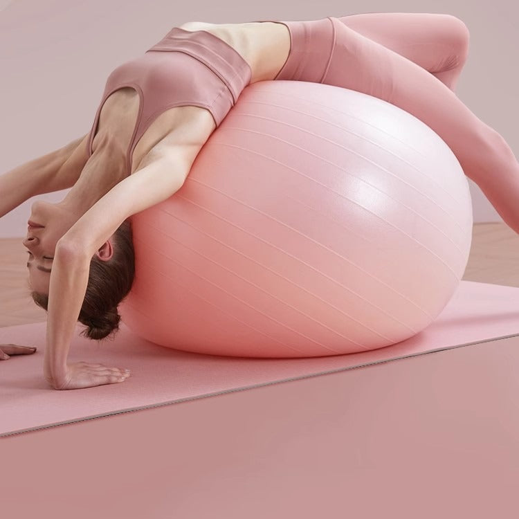 Light pink stability exercise ball with grip lines, used for balance and stretching