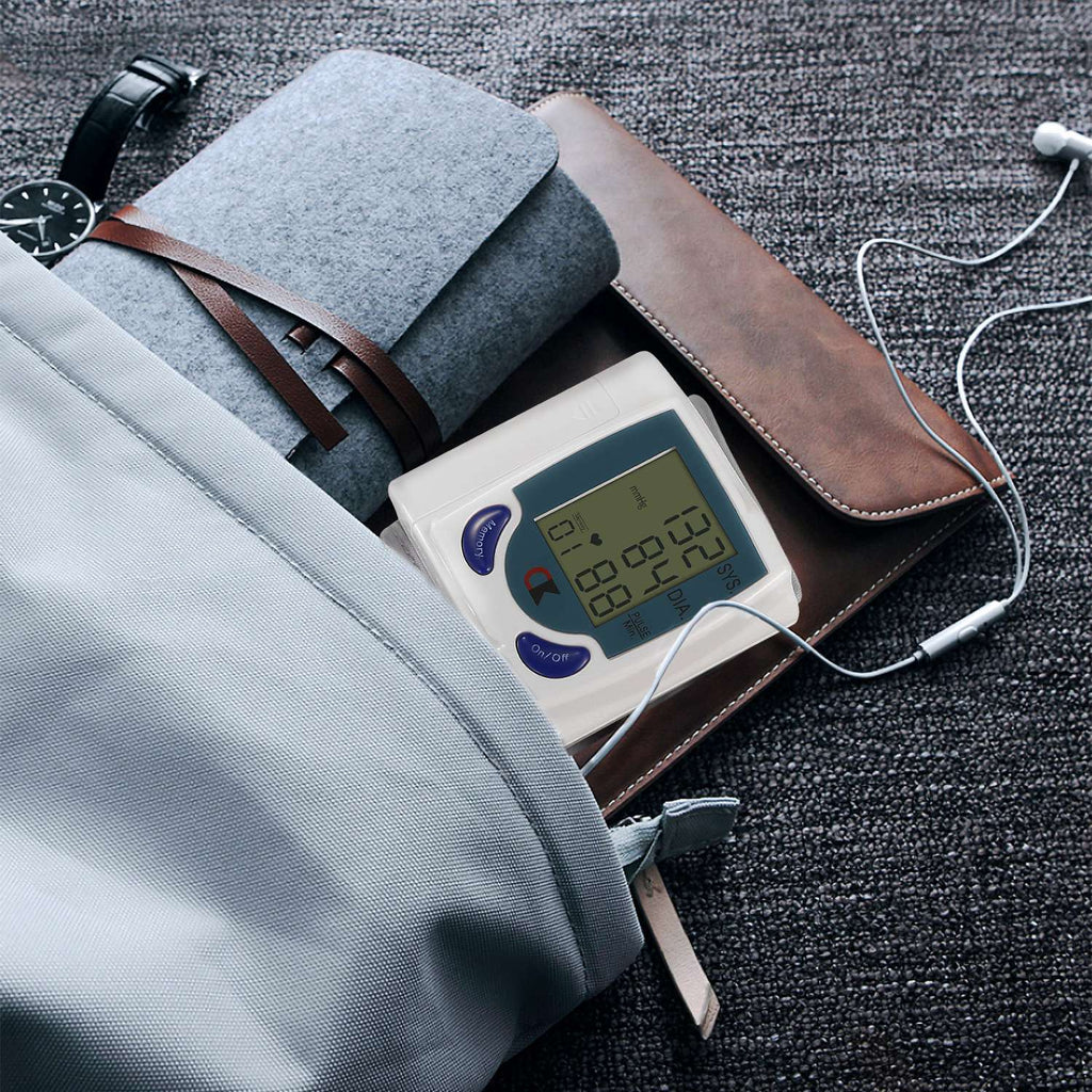 White blood pressure monitor with gray cuff resting on dark fabric on an arm.