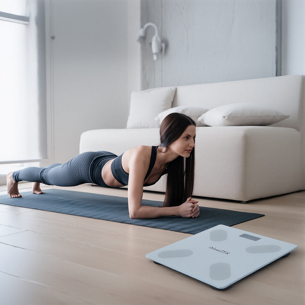 White smart body scale on the floor beside a person doing an exercise plank