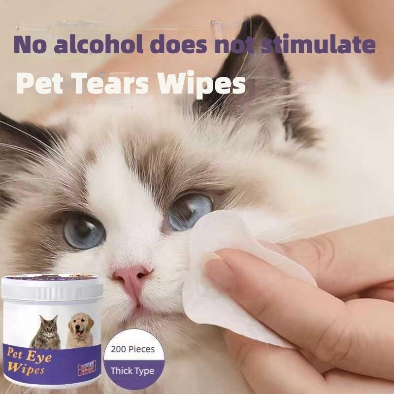 Cat being wiped around the eyes with a white wipe pad held by a hand