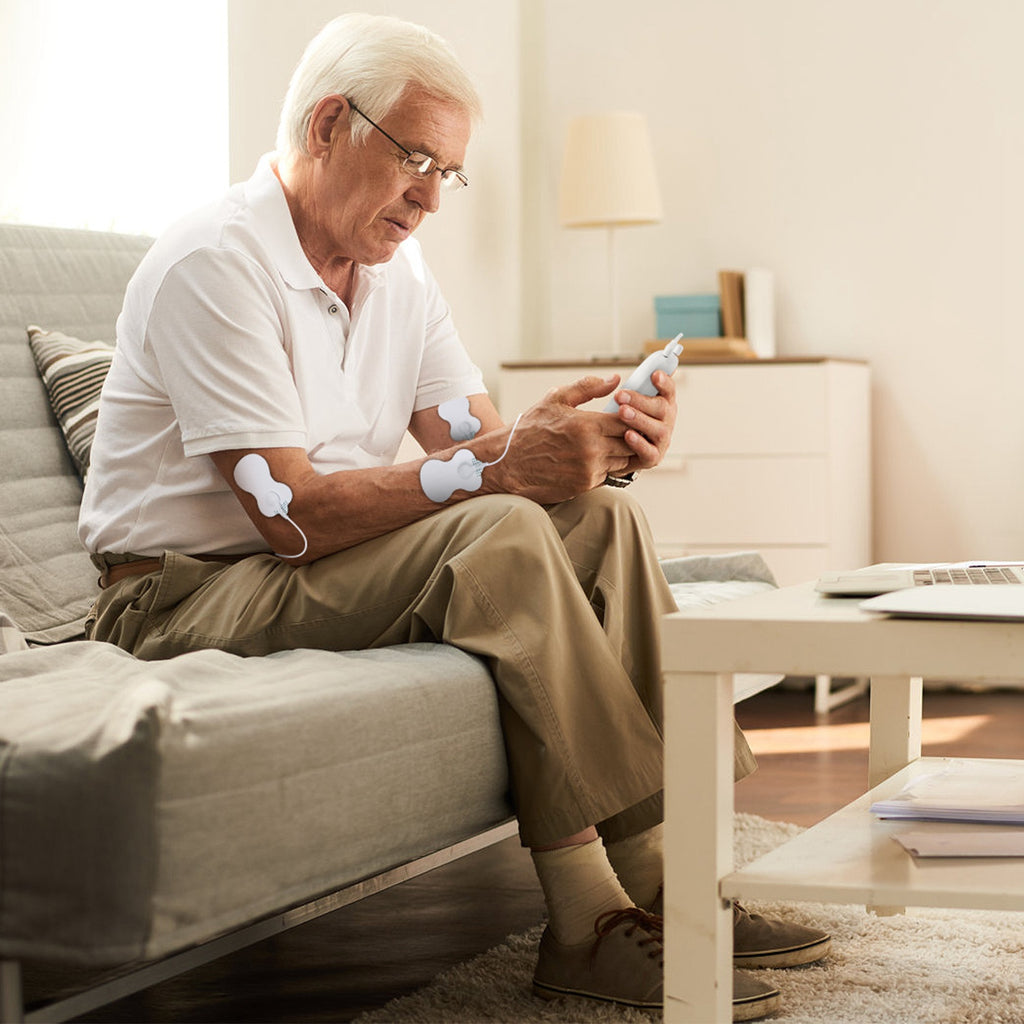 Elder using white wireless stimulator electrodes on legs