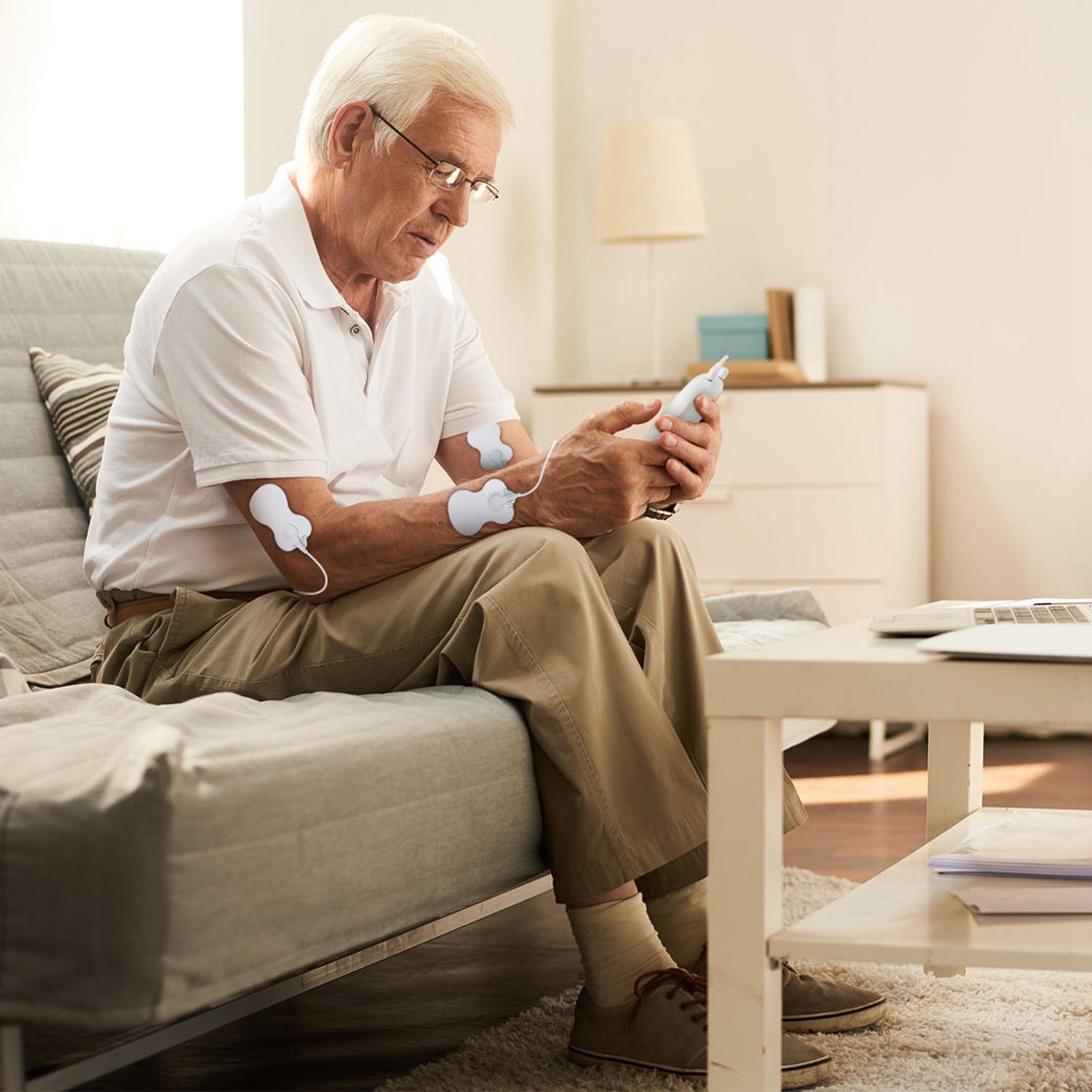 Elder using white wireless stimulator electrodes on legs