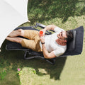 Black padded recliner chair with headrest and reclining frame, shown lying down outdoors.