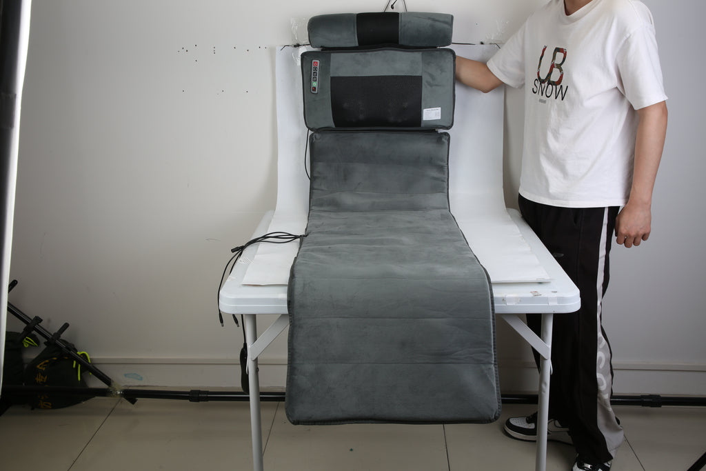 Gray massage mat set up on a table with neck and lumbar headrest cushions