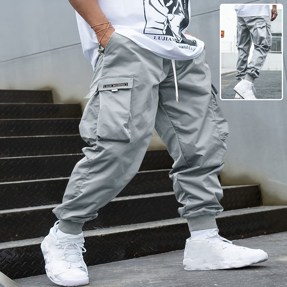 Light gray cargo pants with drawstring hem and multi-pocket utility design