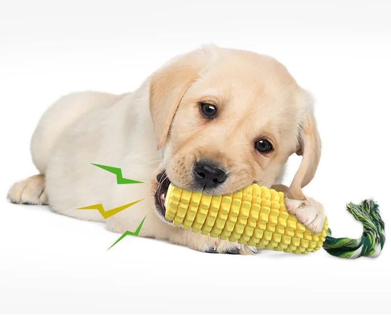 Yellow ridged corn chew toy with green cotton rope tail next to a golden puppy