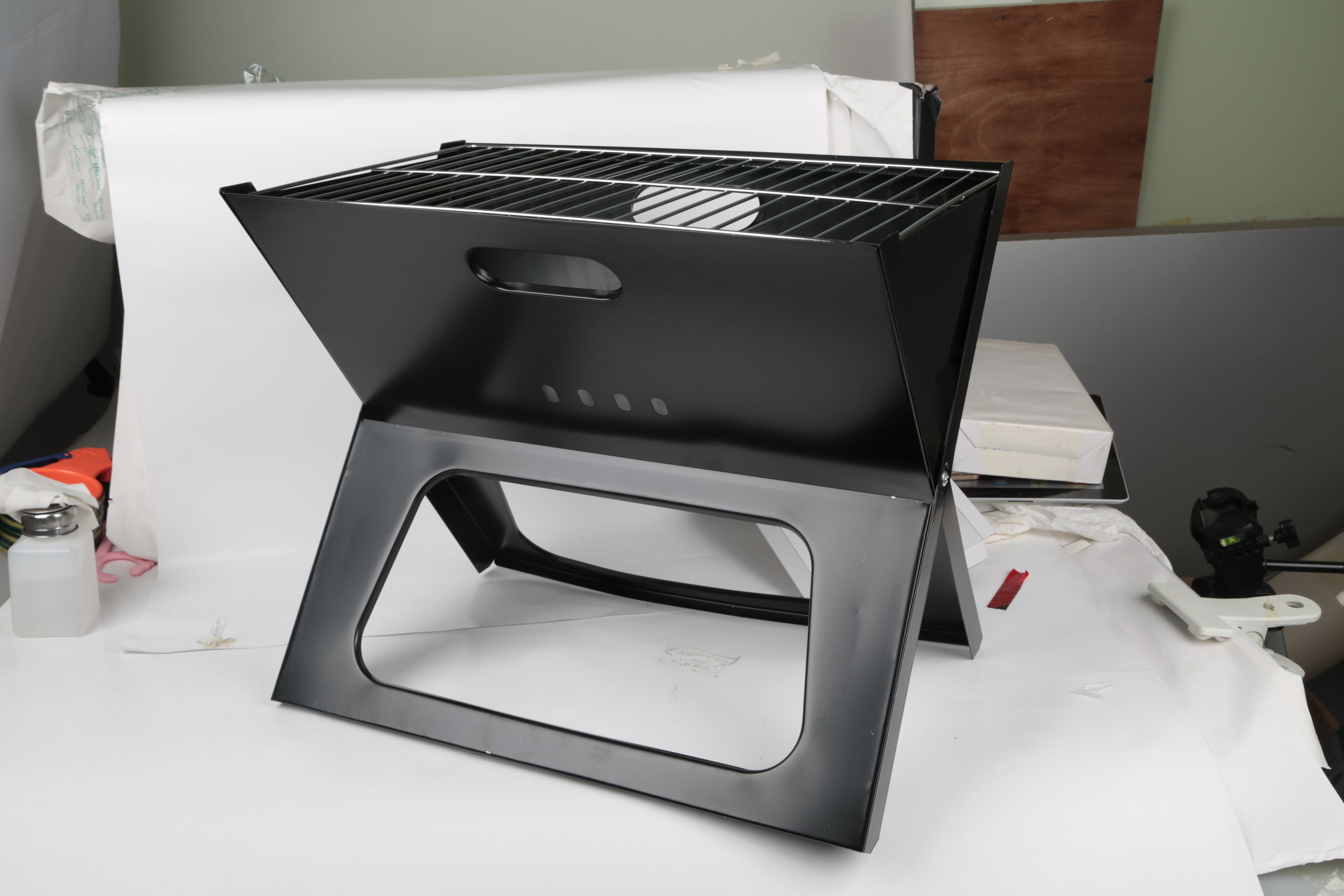 Black portable charcoal BBQ grill, folded stand with front carry handle cutout